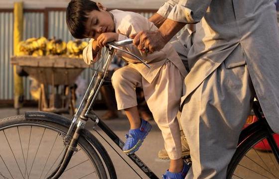تصویری جالب از خواب پسربچه افغان روی دوچرخه + عکس