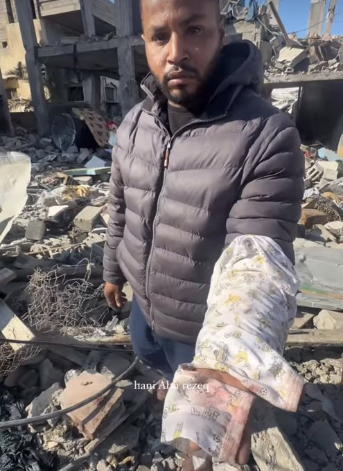 مرد فلسطینی با لباس نوزادش که هرگز چشم به جهان نگشود+عکس