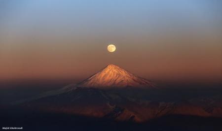 تصویری از دماوند باشکوه و ماه بالای سرش