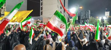  حضور متفاوت یک زن در تجمع شبانه تهران با طوطی سبز با پرچم جمهوری اسلامی ایران+ عکس